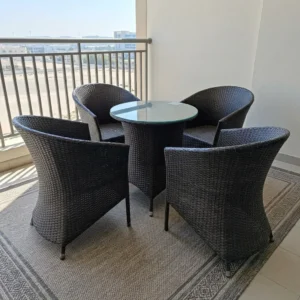 4-Seater Rattan Outdoor Set with four dark woven rattan-style armchairs featuring integrated armrests and a matching round table with transparent glass top