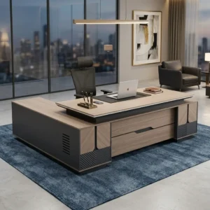 Directors 2.4m Office Desk featuring an L-shaped wooden executive workstation with a light timber grain veneer top, matte charcoal gray side panels, and geometric chevron-milled base accents.