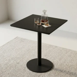 A Modern Pedestal Bistro Table featuring a sleek matte black square top supported by a central black steel pedestal column and a weighted circular base plate.