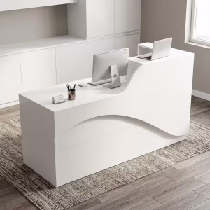 A minimalist all-white Small 1.6m Office Front Desk with a curved privacy panel, holding a desktop computer and laptop in a bright modern office lobby.