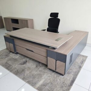 An L-shaped Premium 2.4m Wooden L-Shaped Desk featuring a light oak wood grain top, gray accent panels, a silver cable flip-cover, and an attached side return storage unit.