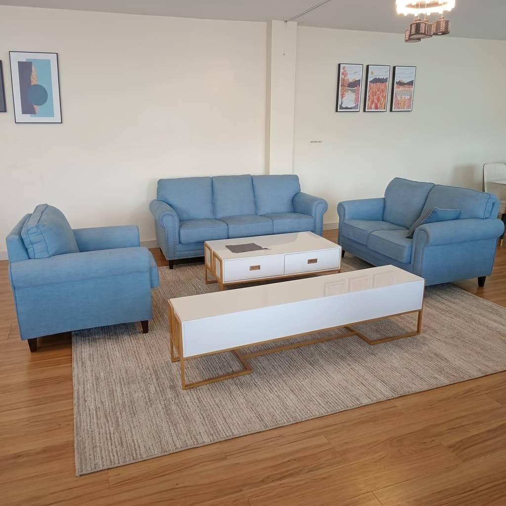 A 6-Seater Blue Sofa Set Upholstered In Sky Blue Woven Fabric, Featuring A Three-Seater Sofa, A Two-Seater Loveseat, And A Single Armchair, All Detailed With Classic Rolled Armrests, Vertical Silver Nailhead Trim, And Tapered Dark Brown Wooden Legs.