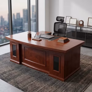 An L-shaped Luxury 2.2m Boss Desk with a reddish-brown wood finish, a central black desk pad, a paneled front modesty board with two vertical glass window inserts, and a side return unit.