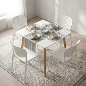 5-Piece White Dining Set featuring a square matte white tabletop with tapered natural wood legs paired with four matching molded white plastic chairs with perforated backrests.